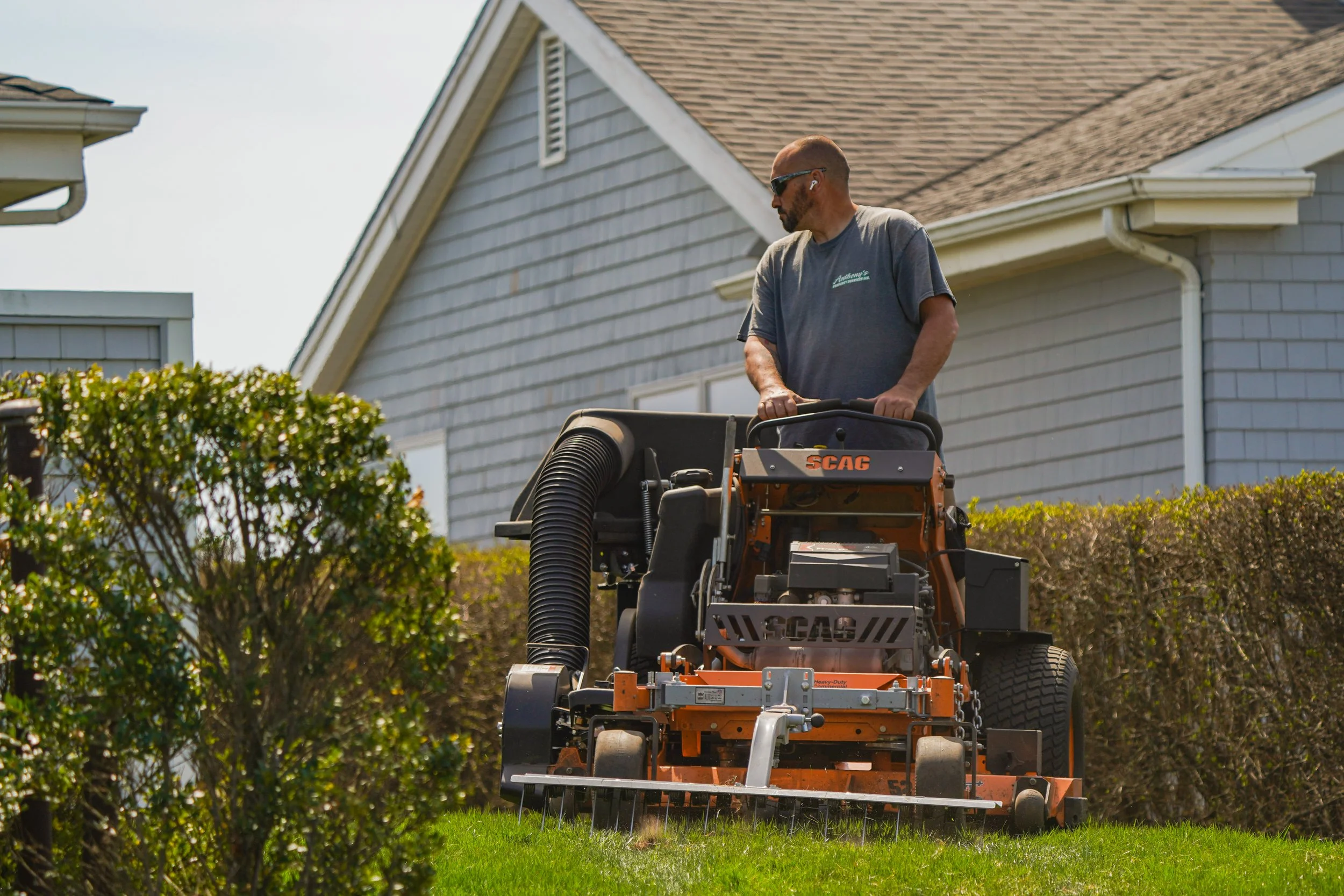 Person using a SCAG lawn mower on grass near a house