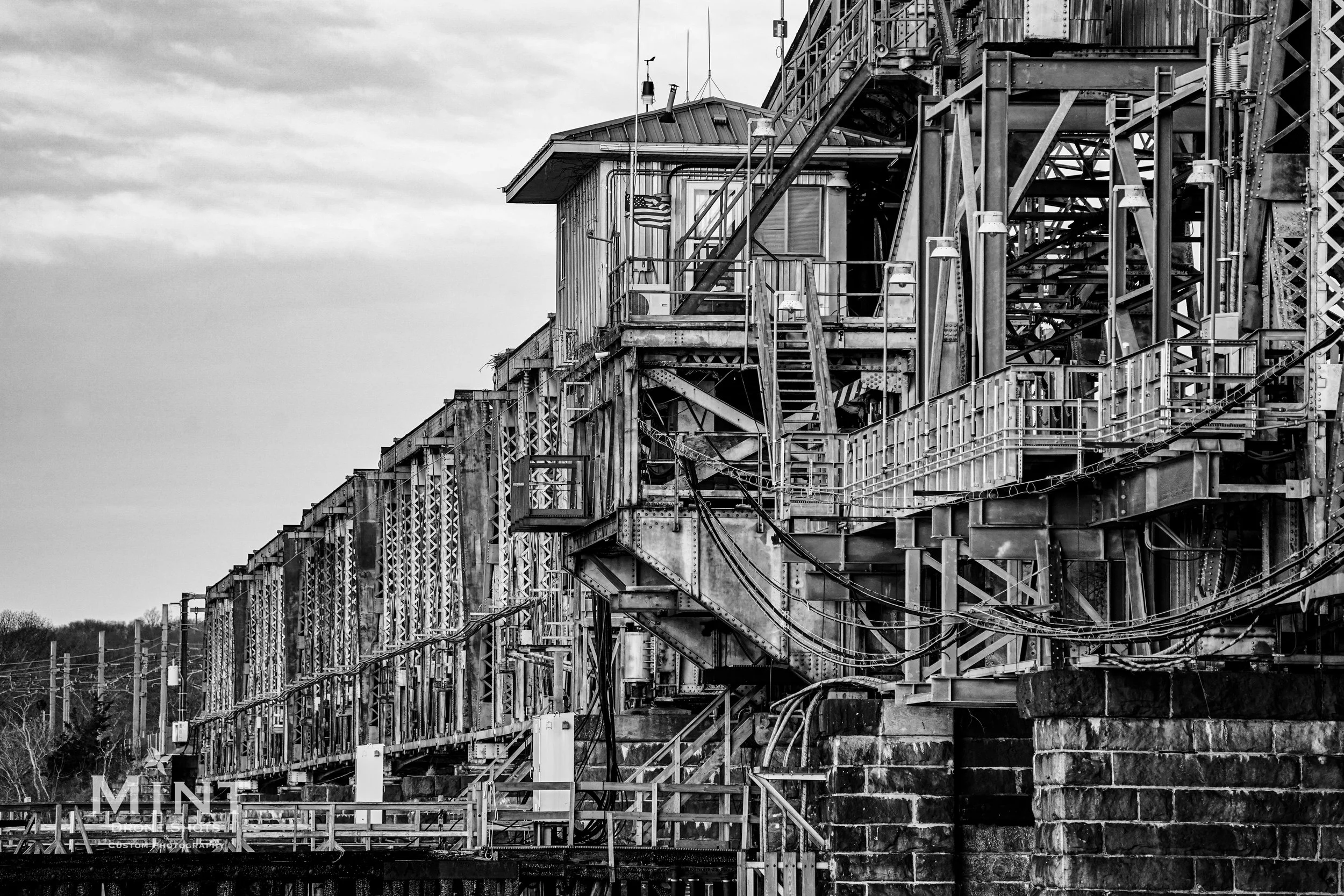 Black and white photo of a metal bridge structure with an industrial design, featuring a control cabin and walkway.