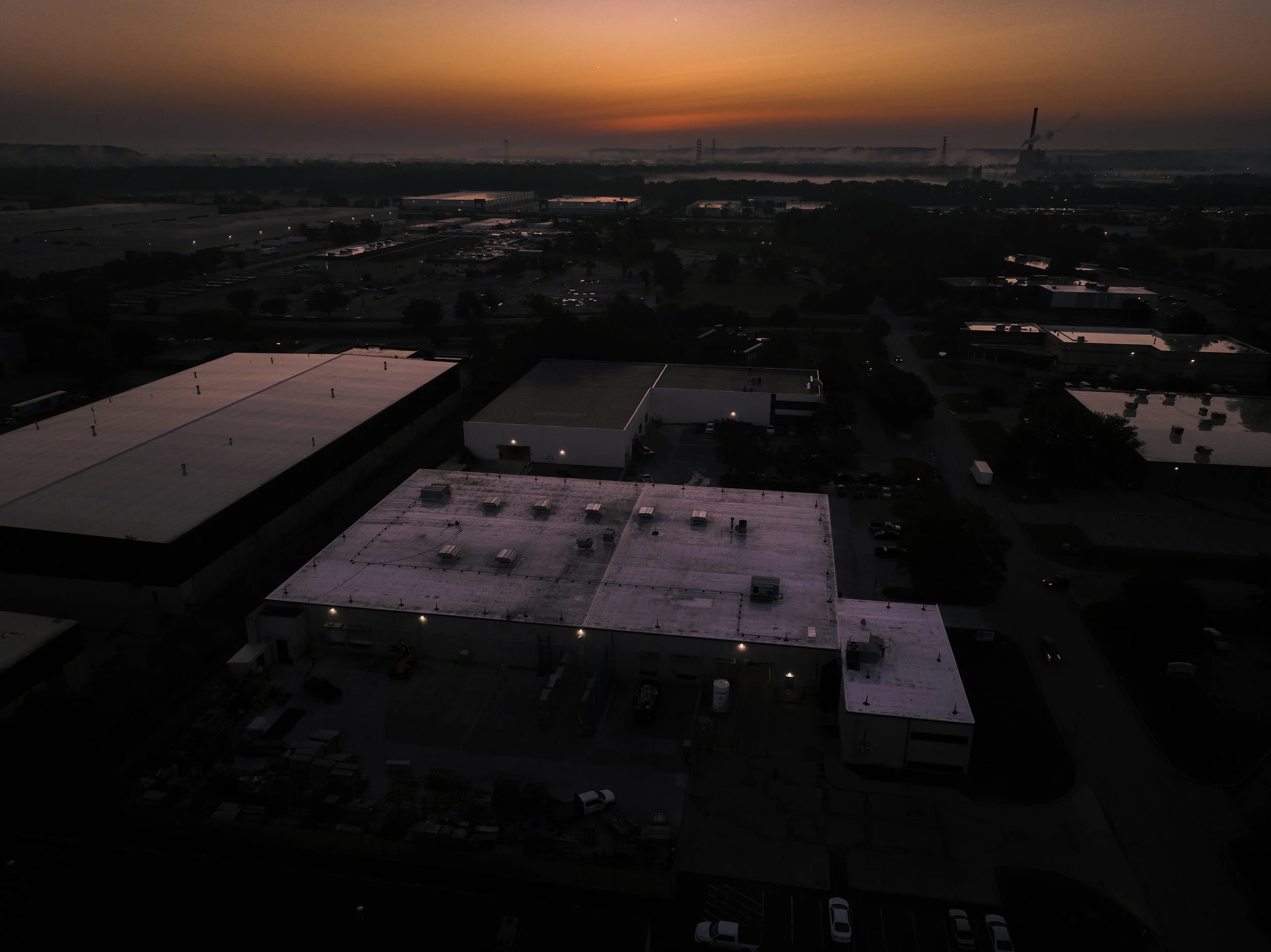 Industrial area at dusk with buildings and a sunset in the background