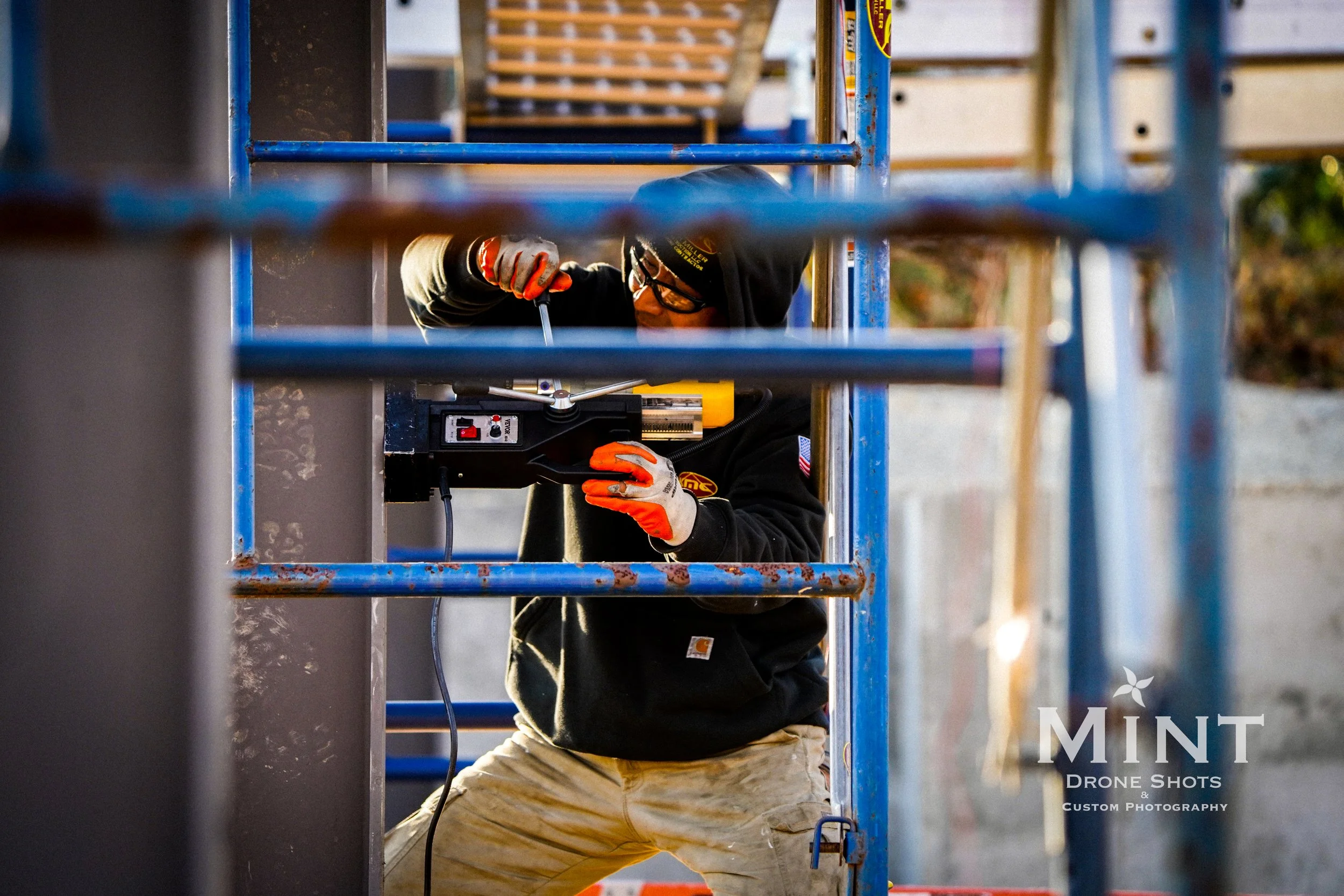 Construction worker using a power tool on a scaffold