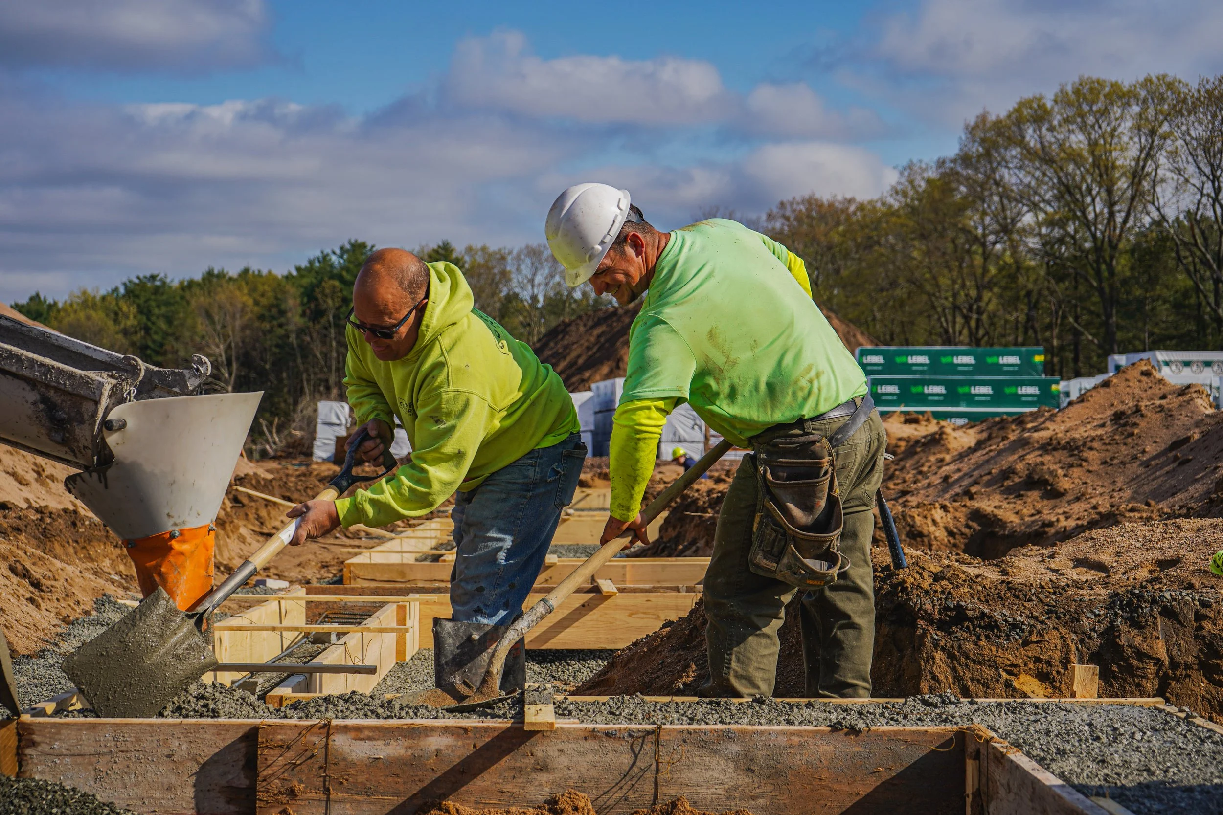 Construction workers pouring concrete into wooden forms at a construction site.