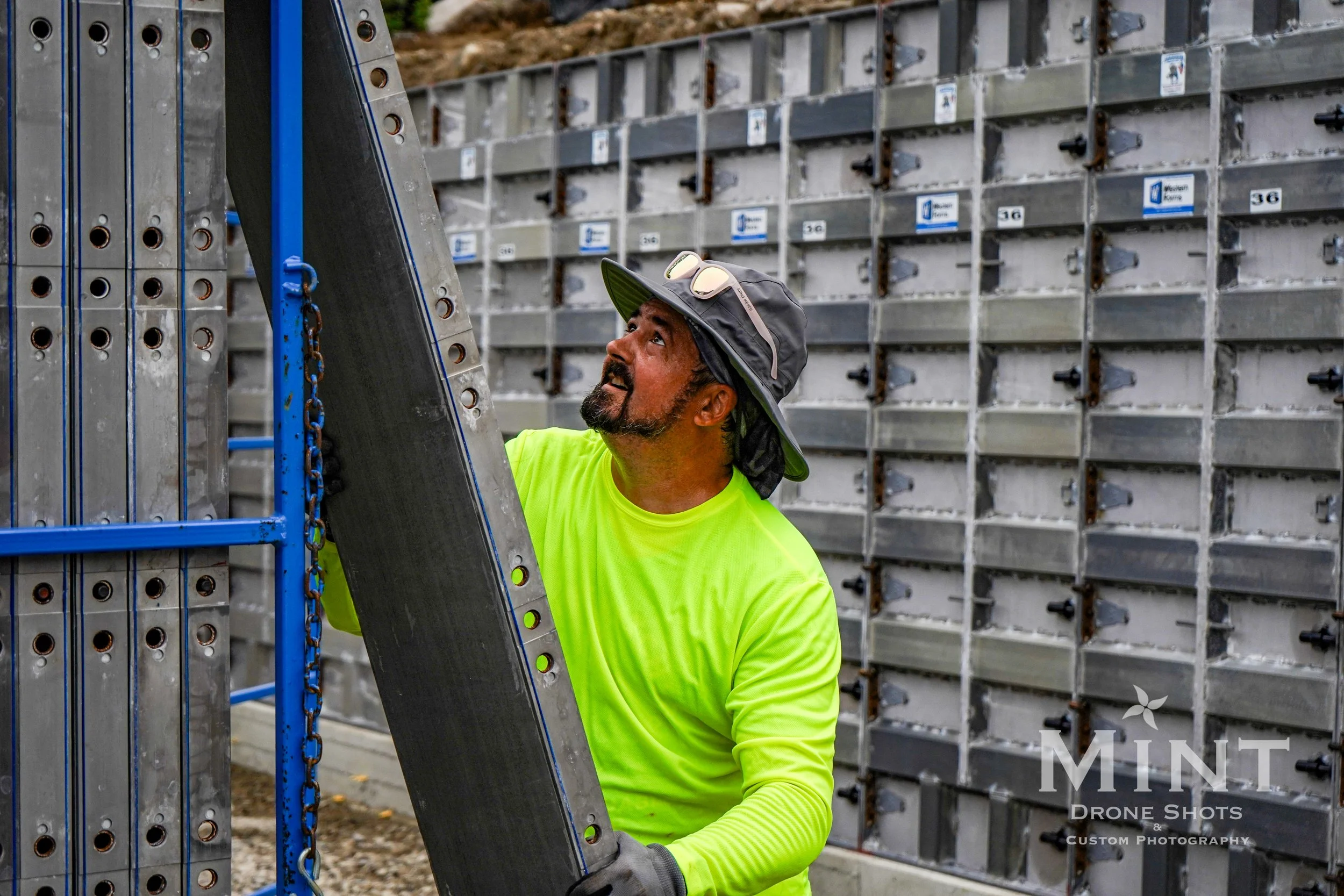 Construction worker in fluorescent shirt adjusting metal framework at building site