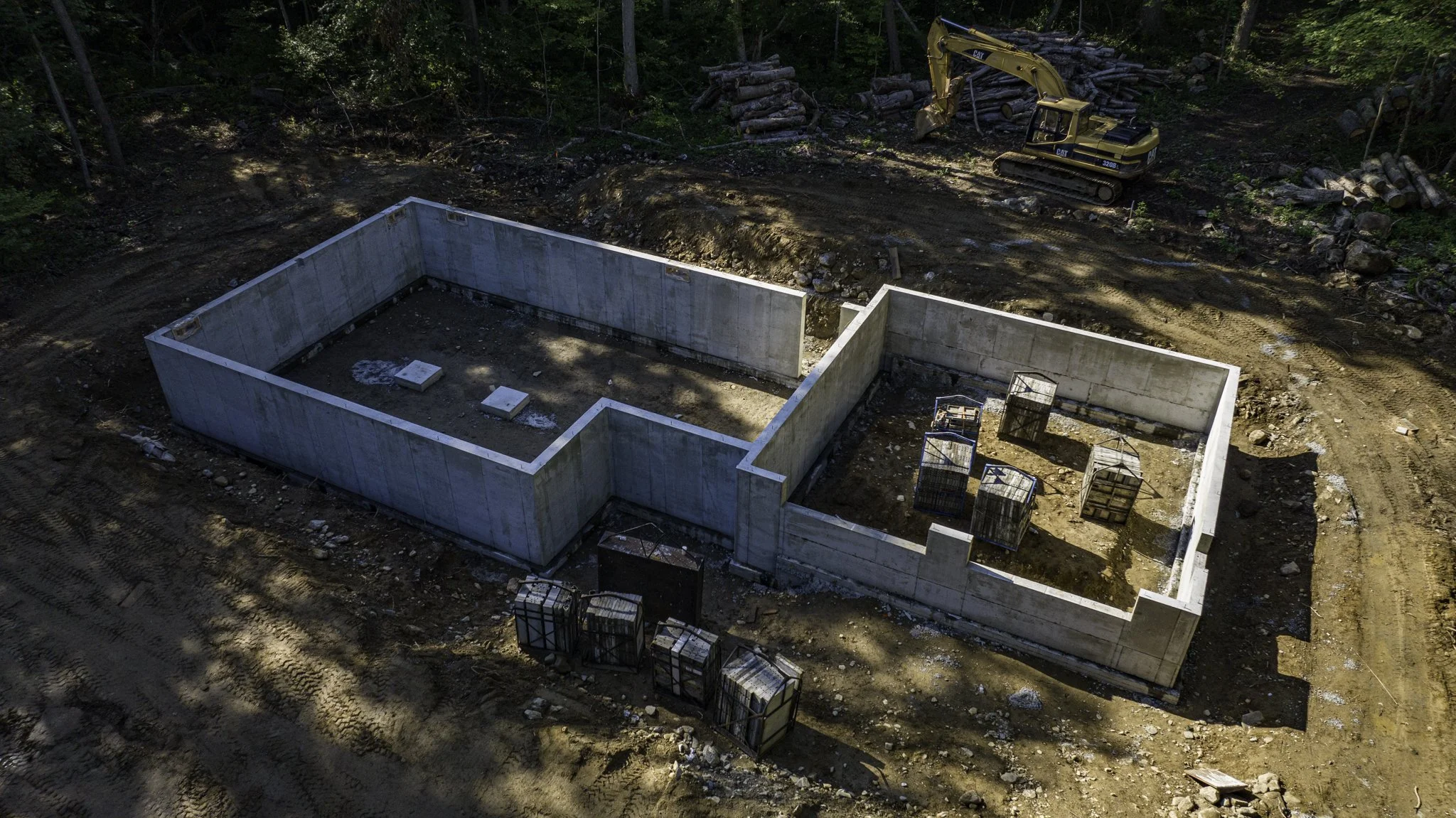 Construction site with concrete foundation walls and excavator