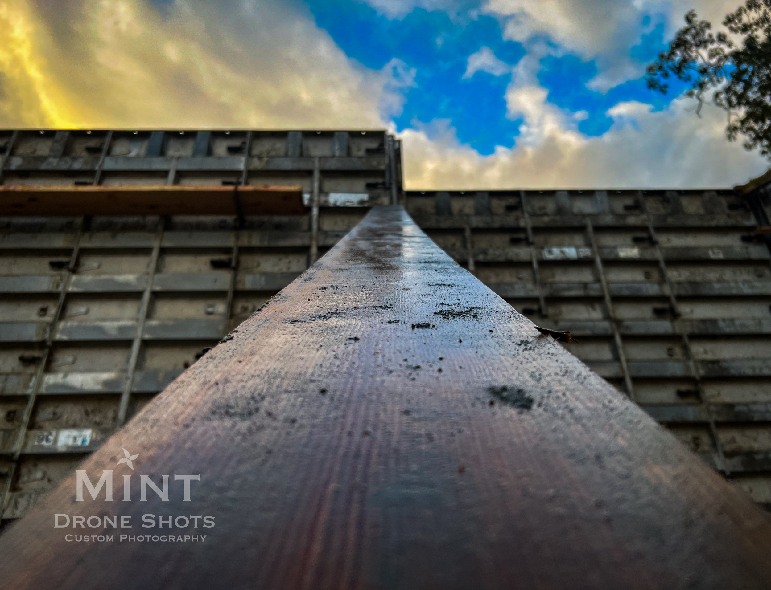 Close-up of a metal beam against a construction site backdrop with cloudy sky.