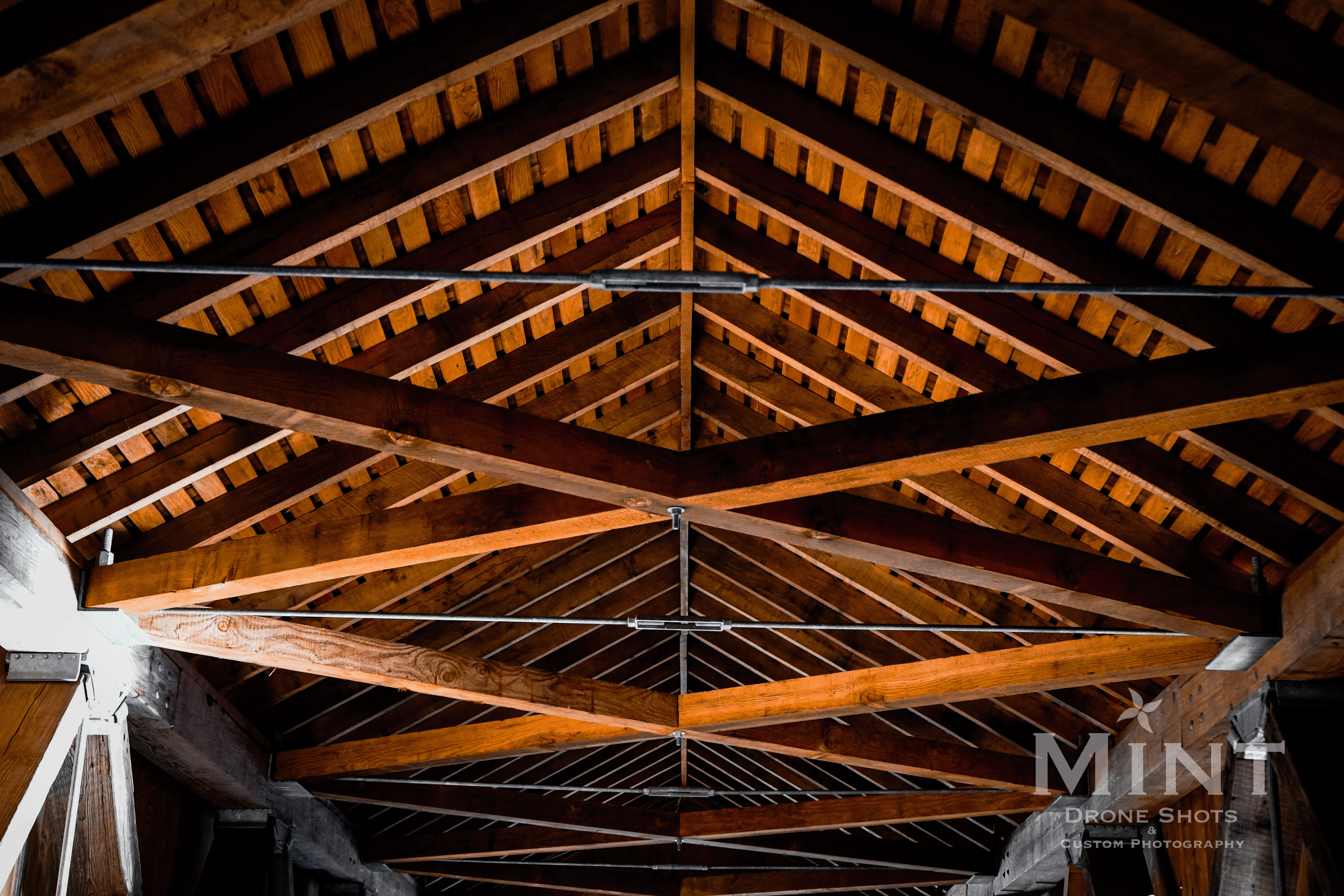 Wooden truss ceiling with exposed beams and rafters in a building.