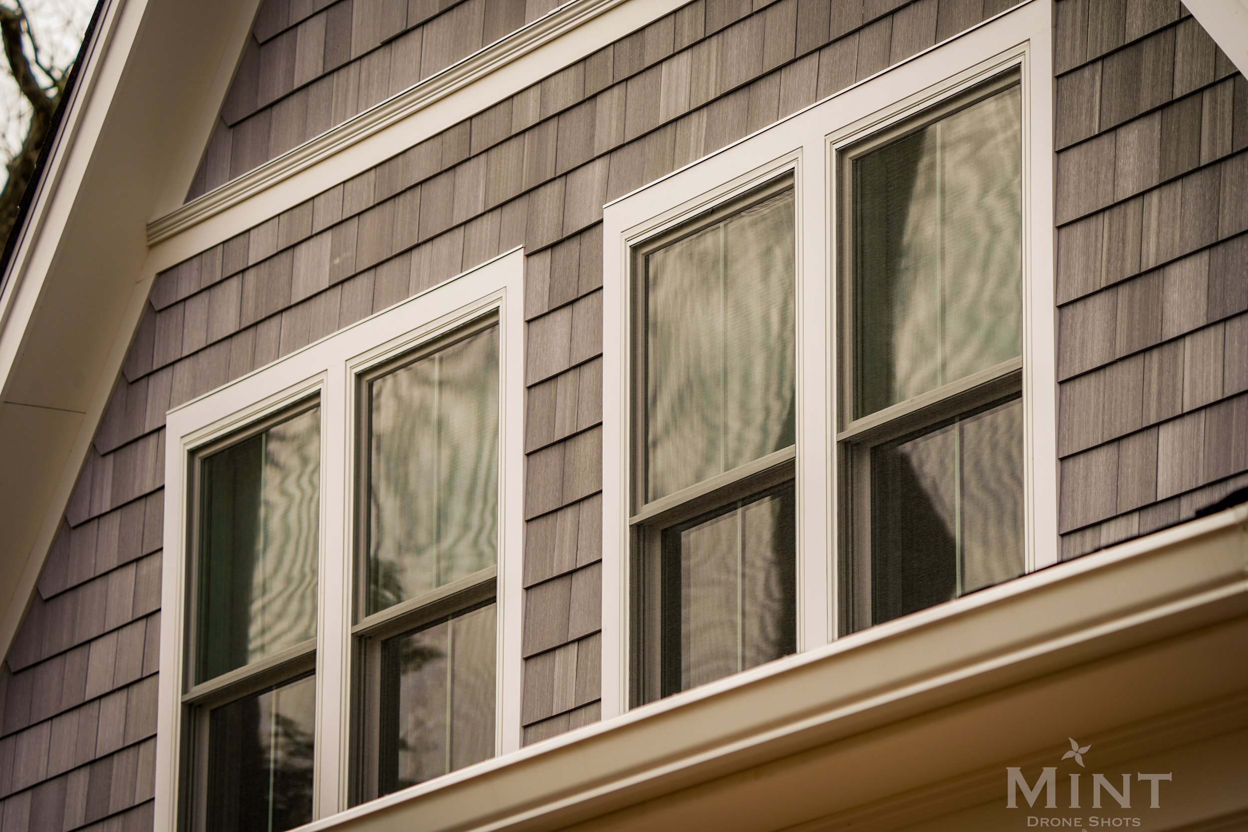 Close-up of three double-hung windows on a house with gray shingle siding.