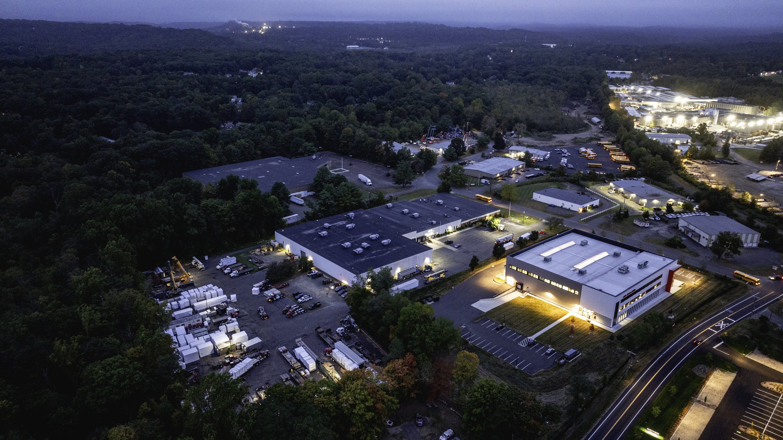 Aerial view of industrial complex at dusk with surrounding forest