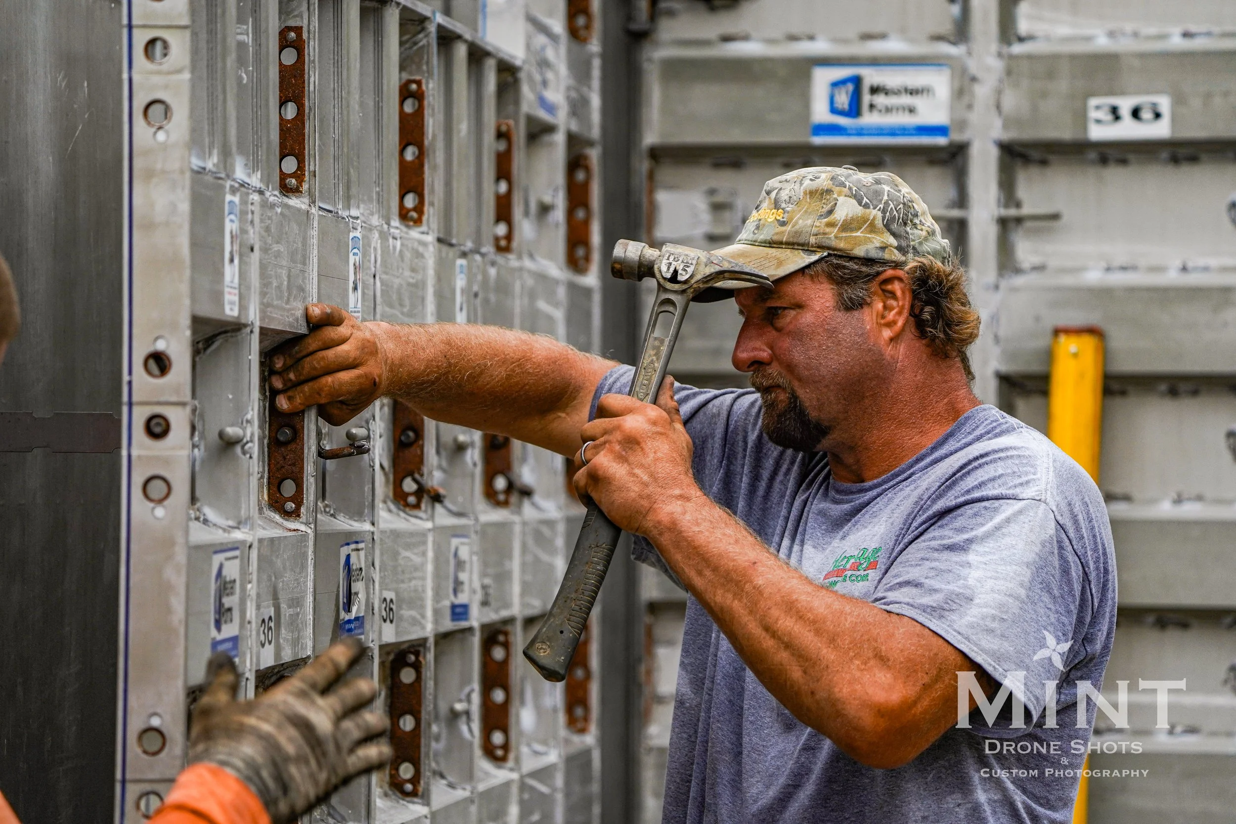 Construction worker using a hammer on a metal formwork wall.