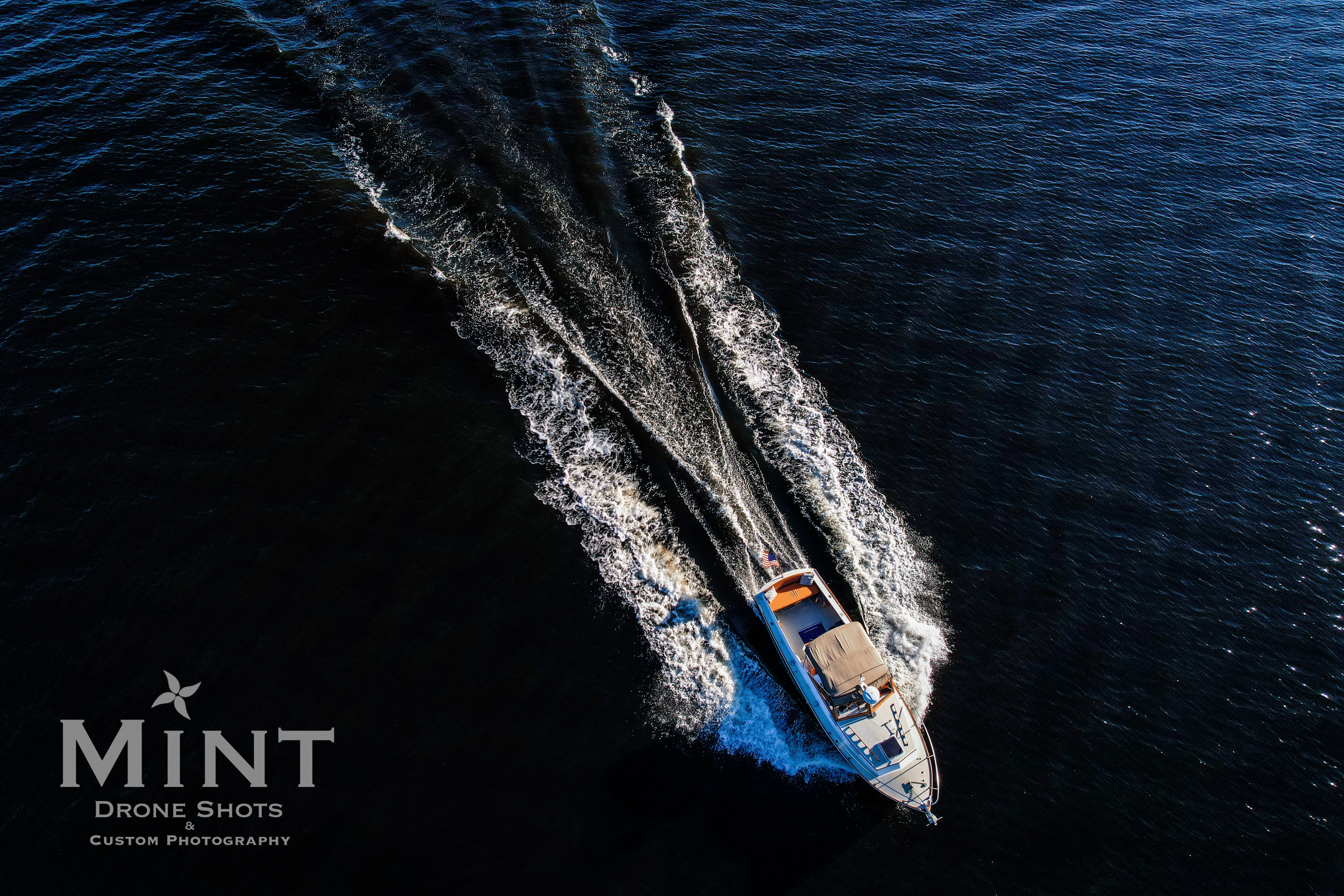 Aerial view of a motorboat leaving a wake on dark blue water.