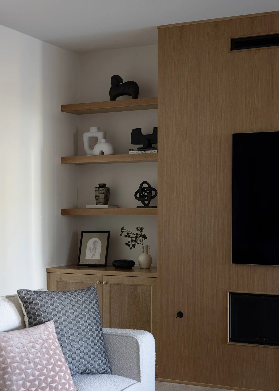 timeless entry experience. Light oak wood treads and handrails are paired with clean black iron balusters for a refined contrast, while soft neutral walls and layered textures keep the space calm and inviting. A sculptural pedestal table, organic cer