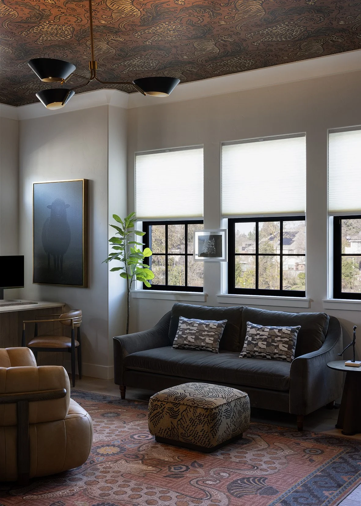 This modern home office and lounge was designed as a warm, multifunctional retreat that balances productivity with comfort. A tailored charcoal sofa, rich leather seating, and layered textiles create a cozy, residential feel, while the custom desk ar