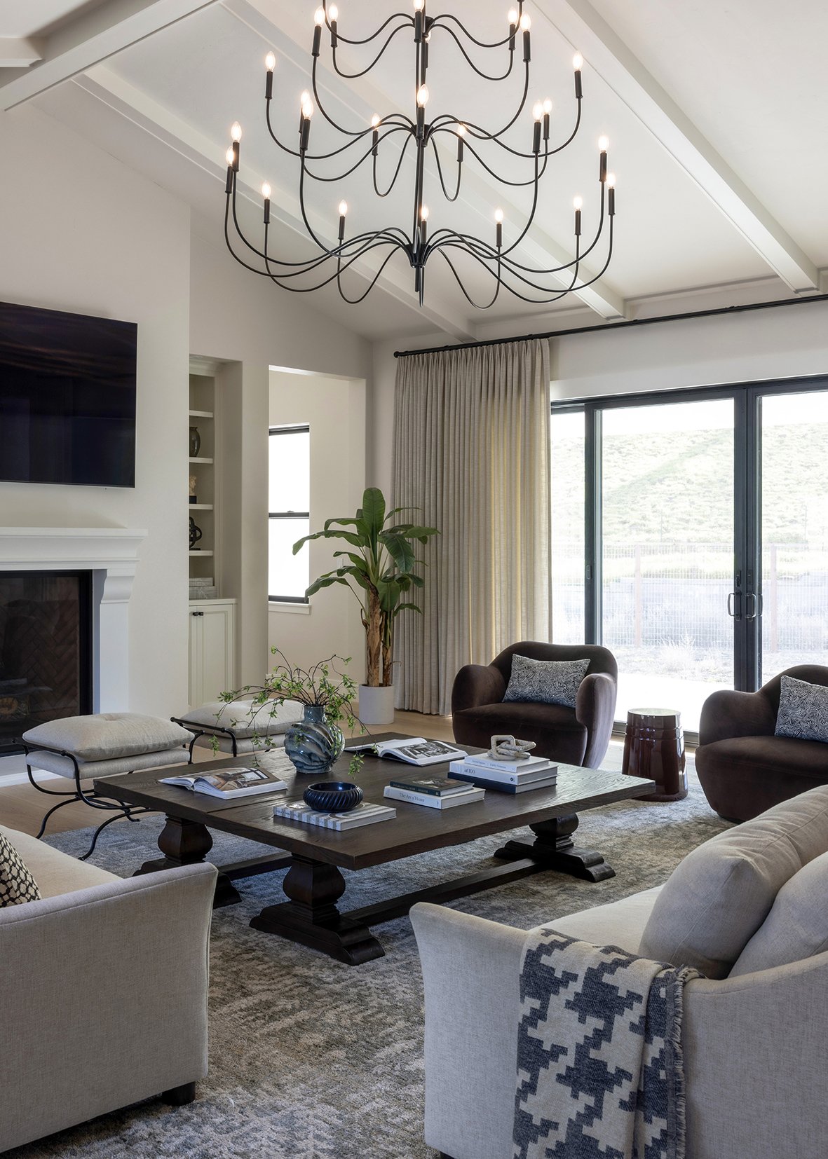 This modern living room was designed as a warm and welcoming gathering space that balances comfort with refined, architectural detail. A custom oversized coffee table anchors the seating area, surrounded by soft neutral upholstery, sculptural lounge 