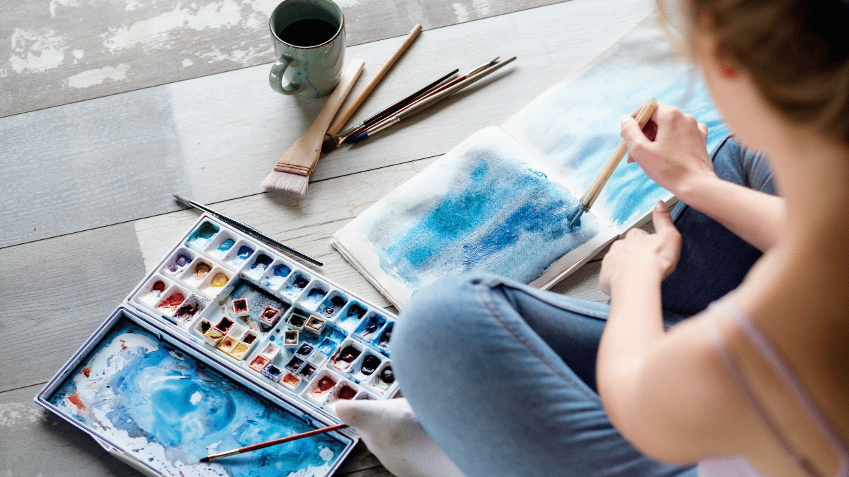Woman creating a water color image while in art therapy session.