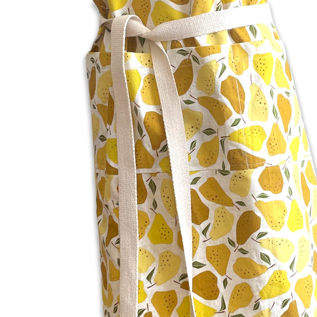 Close-up of a fabric apron with lemon print and beige ties.