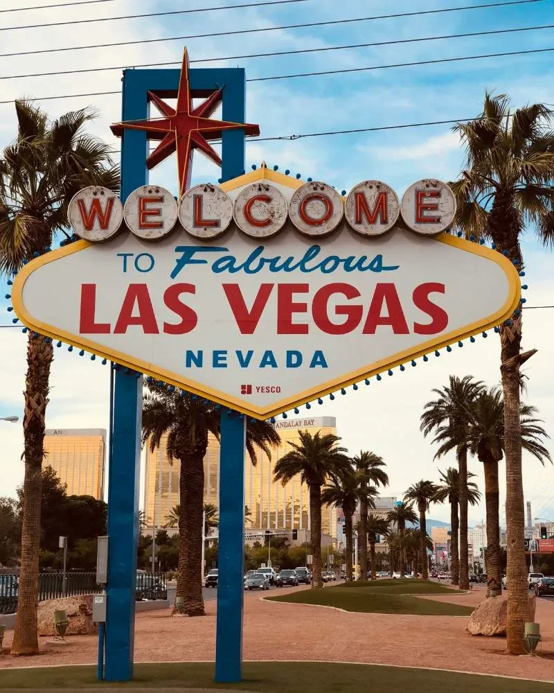The iconic Welcome to Fabulous Las Vegas, Nevada sign with palm trees and city buildings in the background.