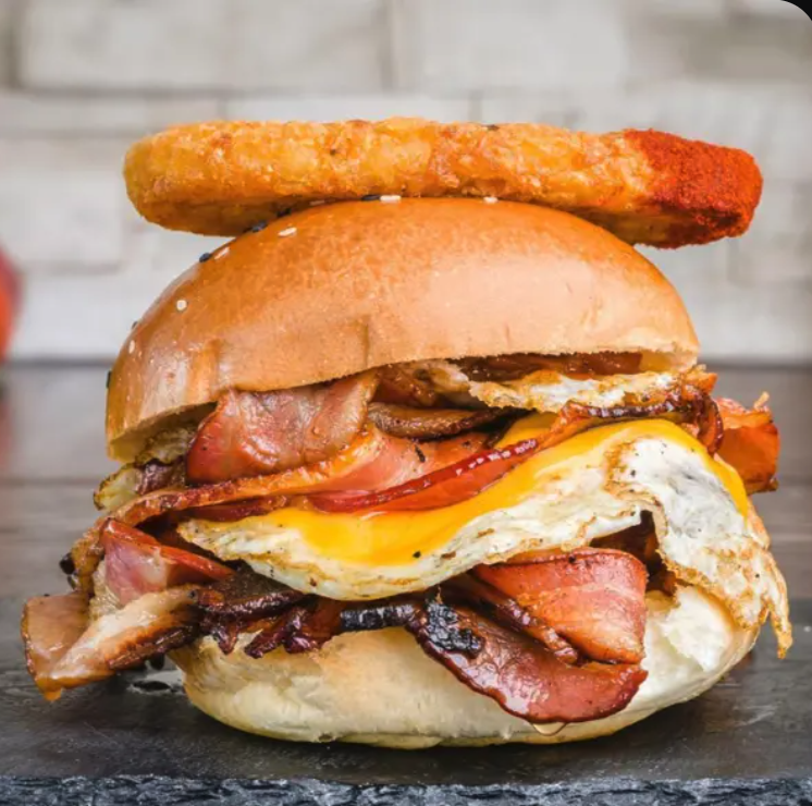 𝗗𝗘𝗟𝗨𝗫𝗘 𝗕𝗥𝗘𝗞𝗞𝗜𝗘 𝗕𝗨𝗥𝗚𝗘𝗥   Toasted Milk Bun with two fried eggs, double streaky bacon, hash brown & house tomato chutney.