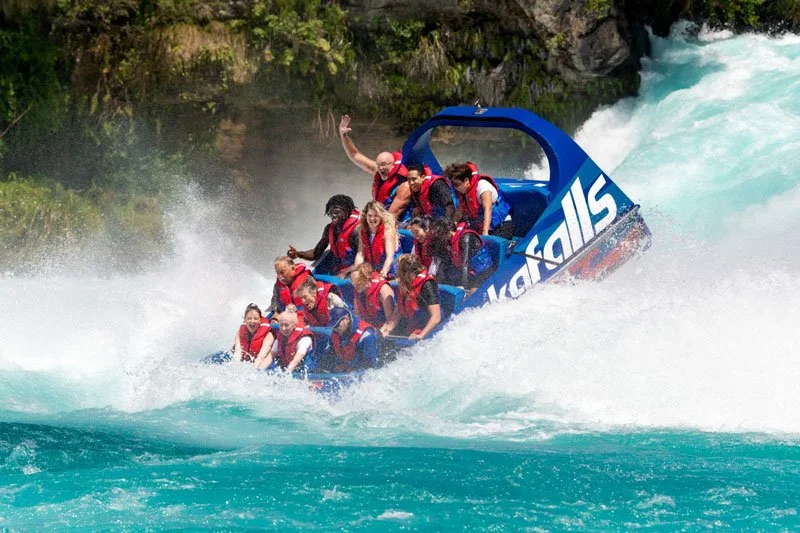 A group of people on a white water rafting boat navigating through rapids.