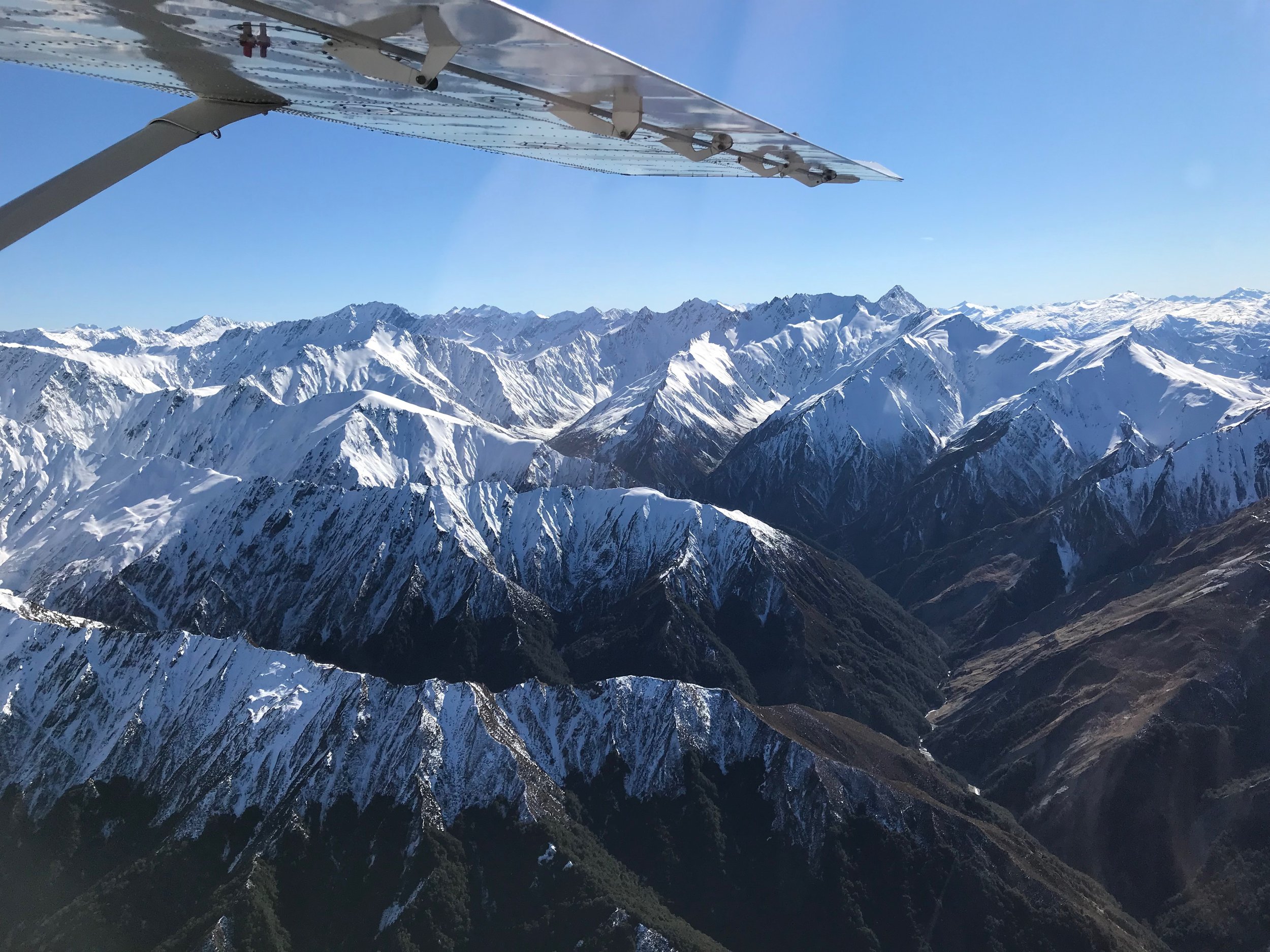 Snow-capped mountain range viewed from an airplane window.