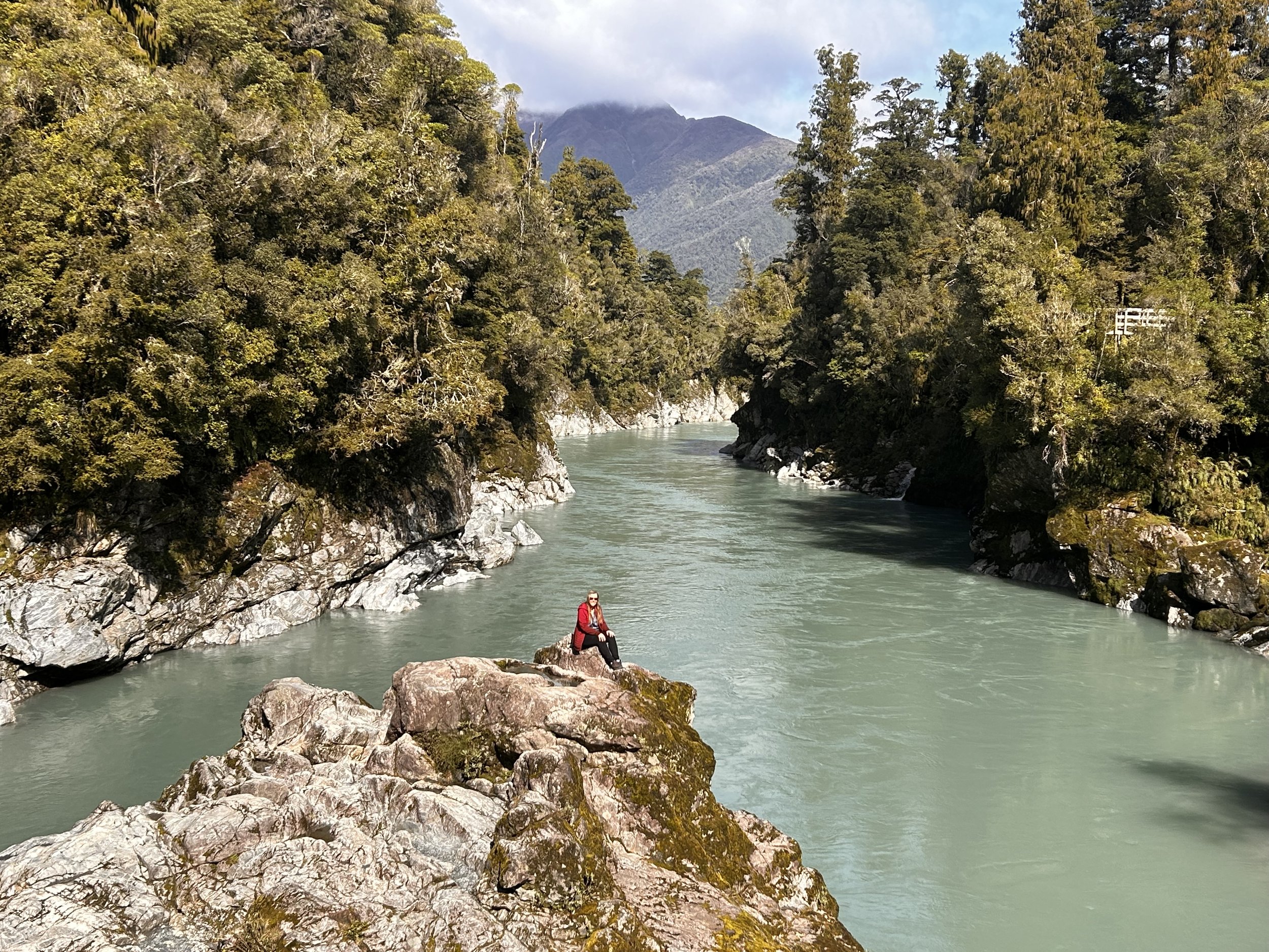 A person sitting on a large rock at the Hokitika Gorge
