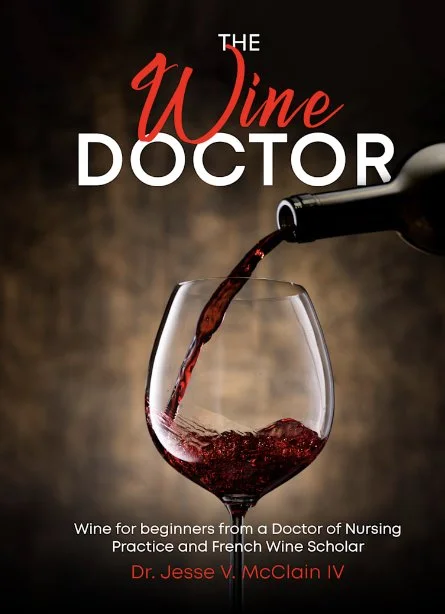 A glass of red wine being poured from a bottle, with the title "The Wine Doctor" and a subtitle about wine for beginners from a nurse and French wine scholar, Dr. Jesse V. McClain IV.
