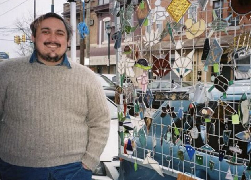 artist next to his stained glass artwork