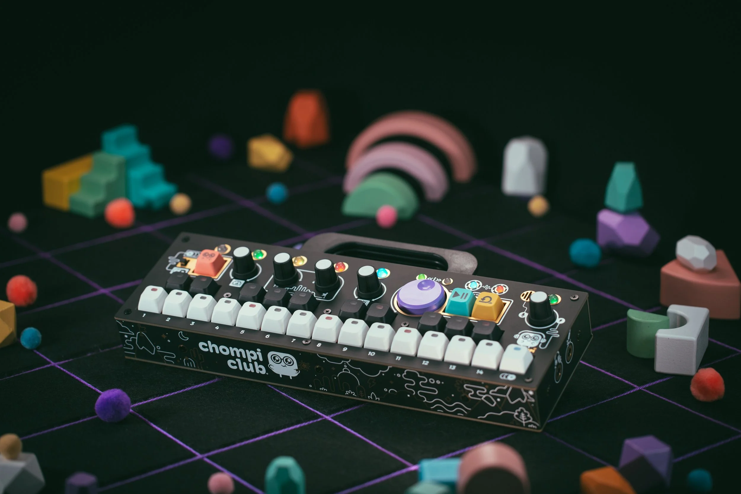 CHOMPI sampler on a black and purple grid surrounded by little toys.