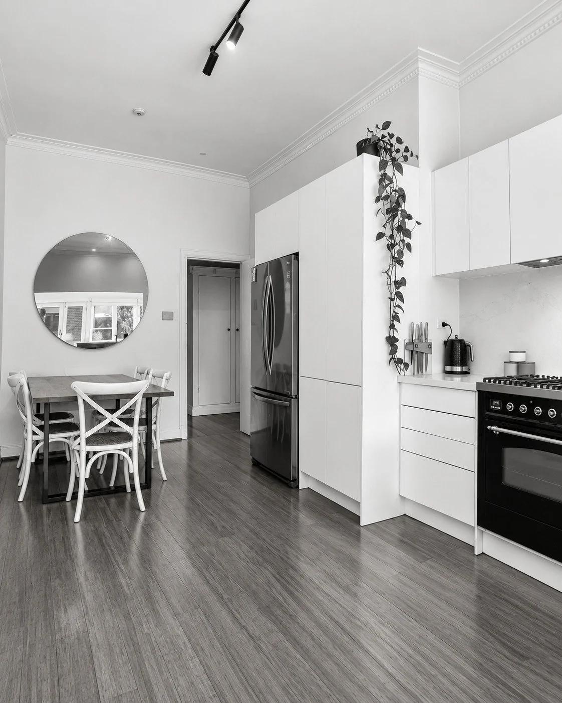 Botanica original kitchen with white cabinetry, a rounded doorway and a small dining area.