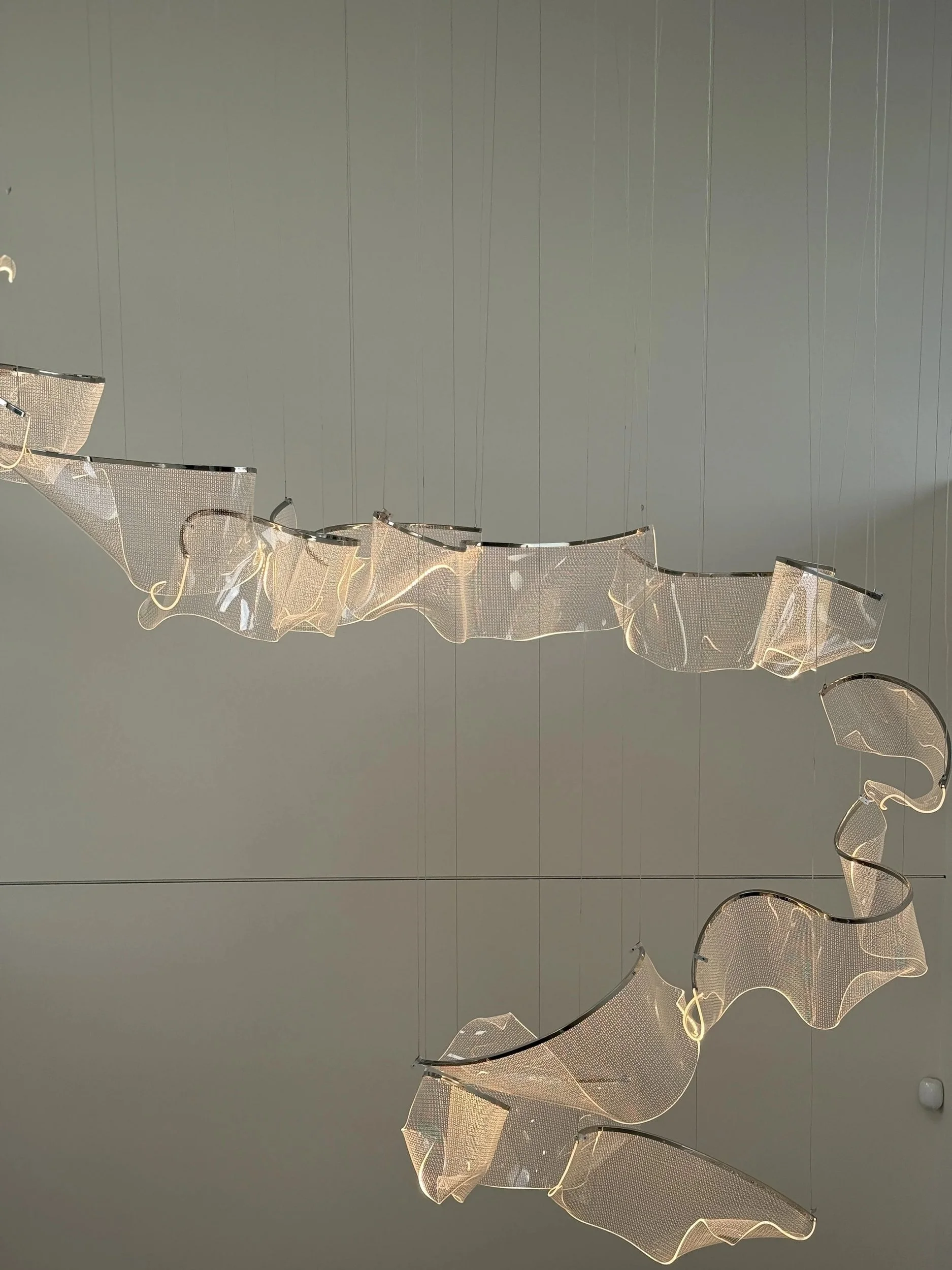 Detail of a sculptural illuminated pendant with irregular flowing forms.