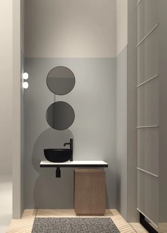 Narrow pale bathroom with a small vanity beneath circular wall details.