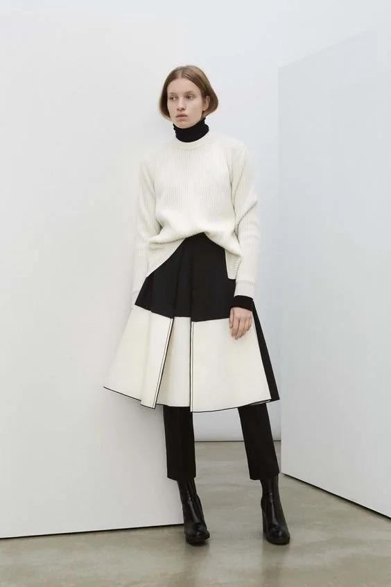 Fashion portrait showing a cream-and-black outfit with tall black boots.