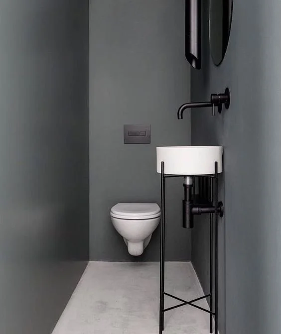 Compact dark bathroom with a small basin and toilet.