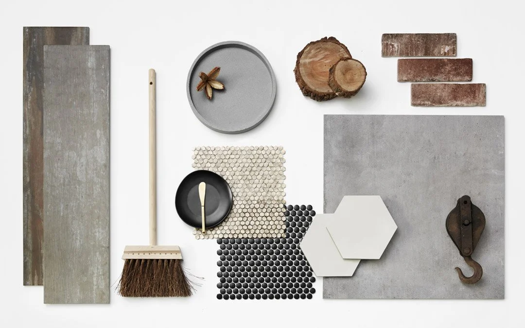 Bathroom sample board with grey tiles, copper-toned pieces and geometric patterns.