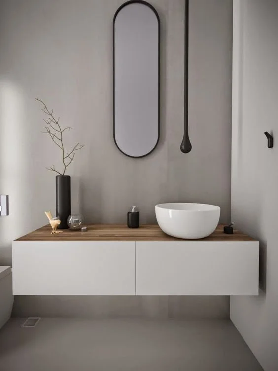 Minimal bathroom with a narrow rounded mirror and white basin on a floating vanity.