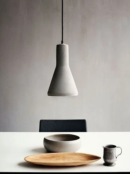 Simple pendant above a table arranged with ceramic bowls and plates.