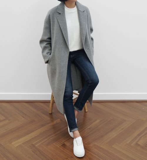 Fashion portrait of a person wearing a grey blazer, jeans and white shoes.