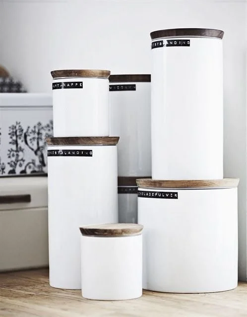 White cylindrical kitchen storage canisters with timber lids.
