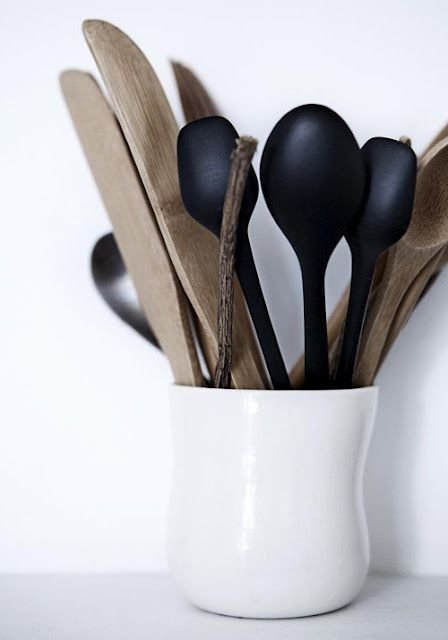 Timber and dark cooking utensils arranged in a white ceramic pot.