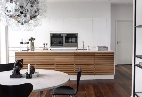 Kitchen with horizontal timber island panelling beside a round dining table.