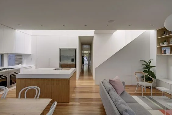 Open-plan kitchen and living room with timber joinery and a grey sofa.