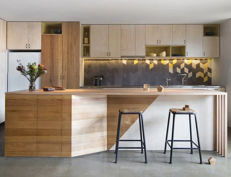 Timber kitchen island with two stools and a decorative metallic splashback.