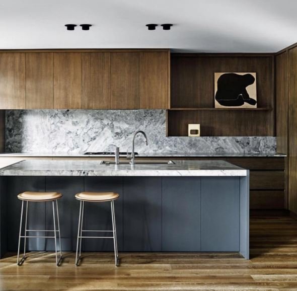 Kitchen with timber cabinetry, a dark island and a veined pale stone splashback.