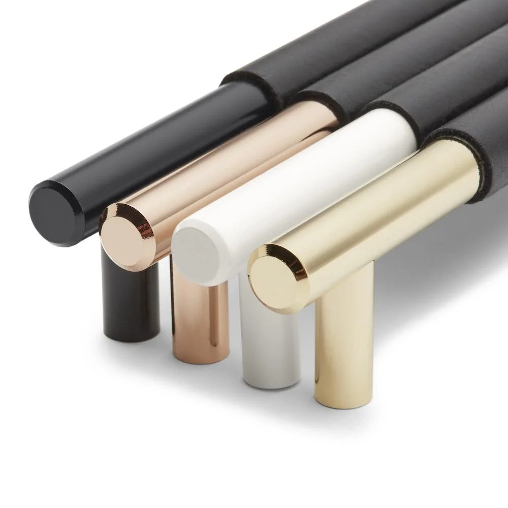 Cylindrical cabinet handles in black, brass-toned, copper-toned and pale finishes.
