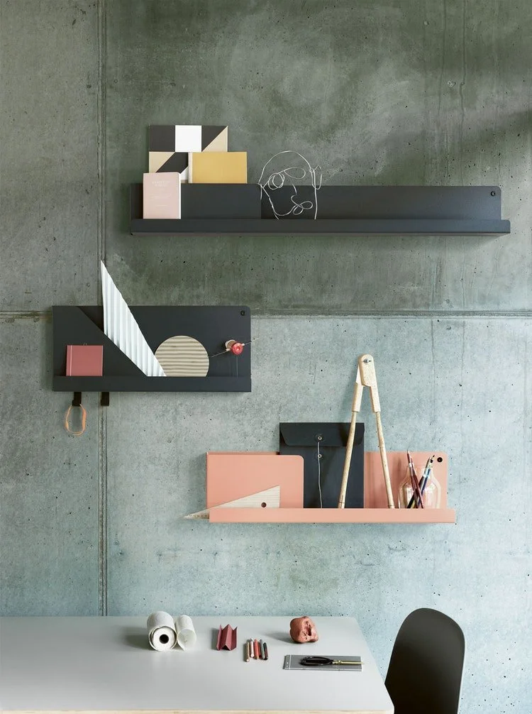 Slim wall shelves displaying books and objects against a textured green wall.