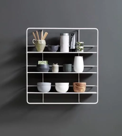 Metal wall rack displaying cups, bowls and utensils against dark grey.