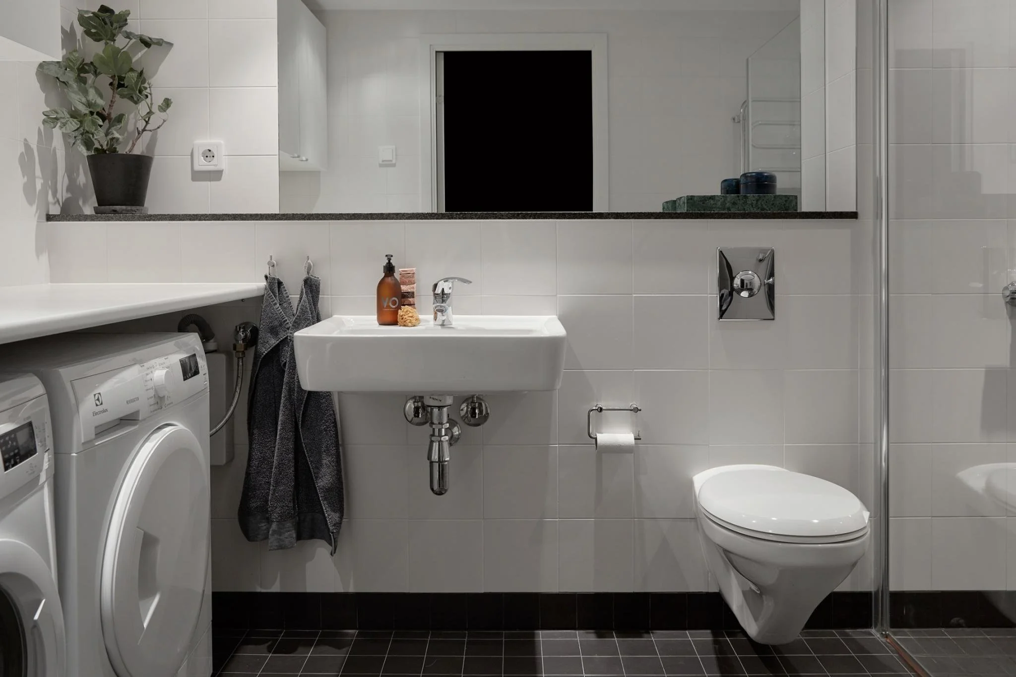 Compact bathroom with a washing machine, small basin and toilet.