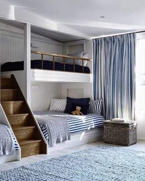 Children’s room with built-in bunk beds, storage steps and blue curtains.