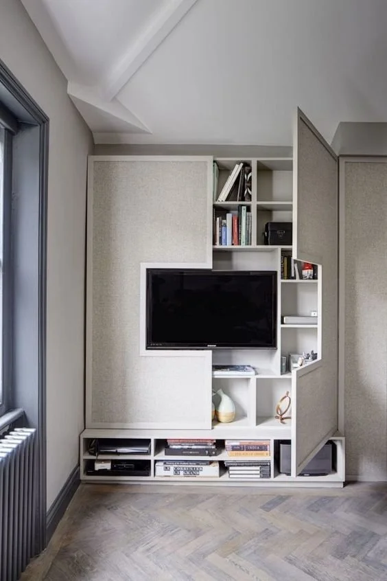 Built-in television and shelving unit within a compact pale room.