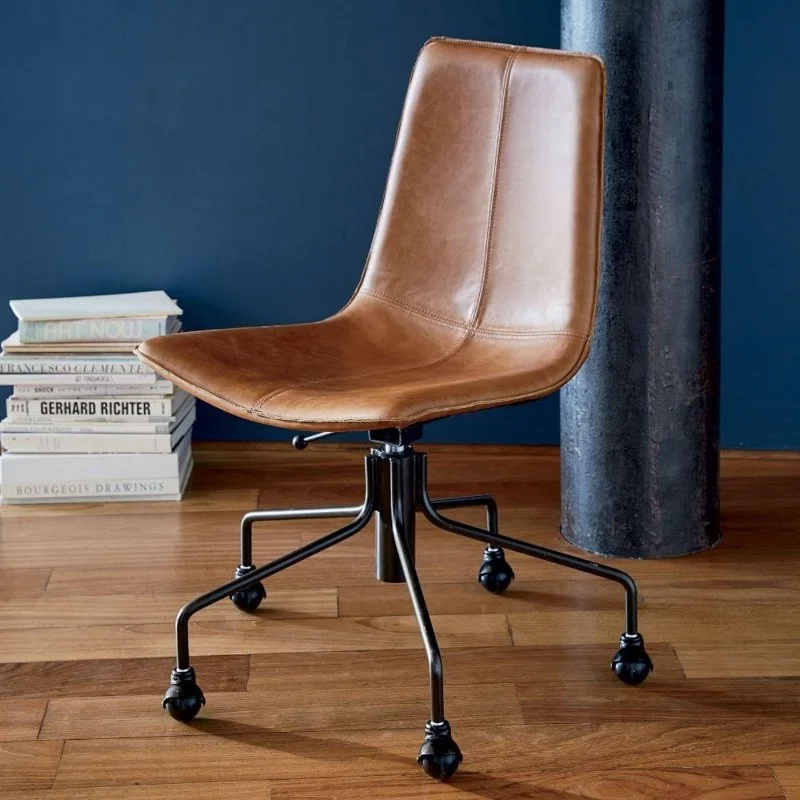 Tan upholstered swivel desk chair on castors beside stacked books.