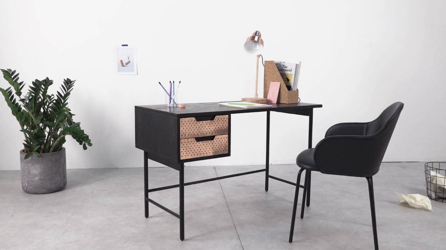 Dark desk with timber drawers and a black chair beside a leafy plant.