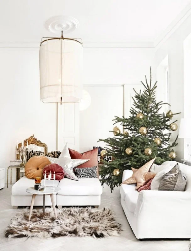 Light living room with a decorated Christmas tree beside pale seating.